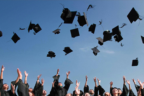Graduates tossing graduation caps into the air