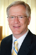 Randy Juhl is wearing a black suit with white shirt and yellow and blue striped tie