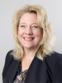 Denise Hill is wearing a multi colored blouse with a dark jacket