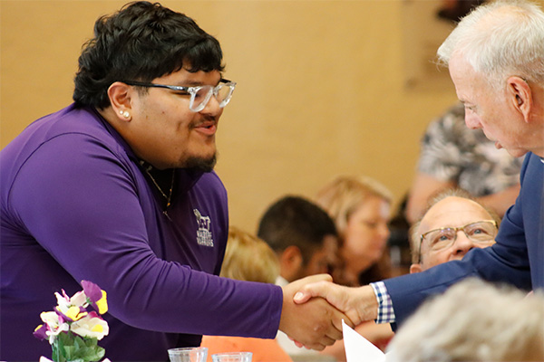 Waldorf scholarship recipient shaking hands with Ray Bebee at award ceremony luncheon